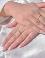 Hand wearing dual-tone crystal wedding band ring on silk fabric