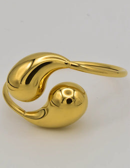 Teardrop gold bracelet bangle resting open on white background