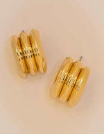 Close-up of polished triple curve gold conch earrings
